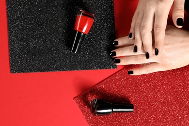 Photo of Woman with black manicure and nail polish bottles on color background, top view. Space for text