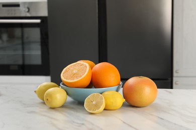 Photo of Allergenic food. Different citrus fruits on light marble table in kitchen