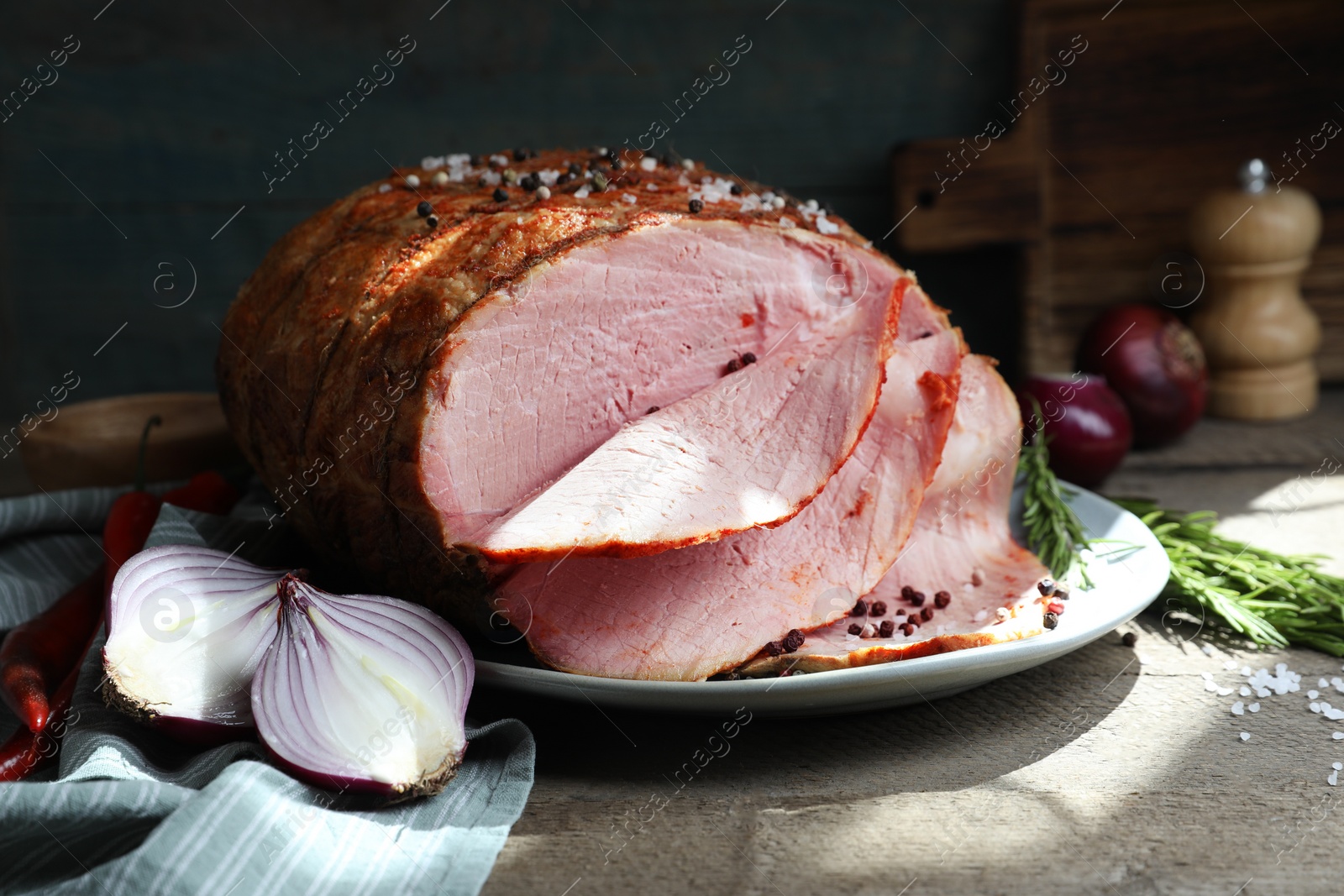 Photo of Delicious baked ham, onion, chili peppers and rosemary on grey wooden table, closeup