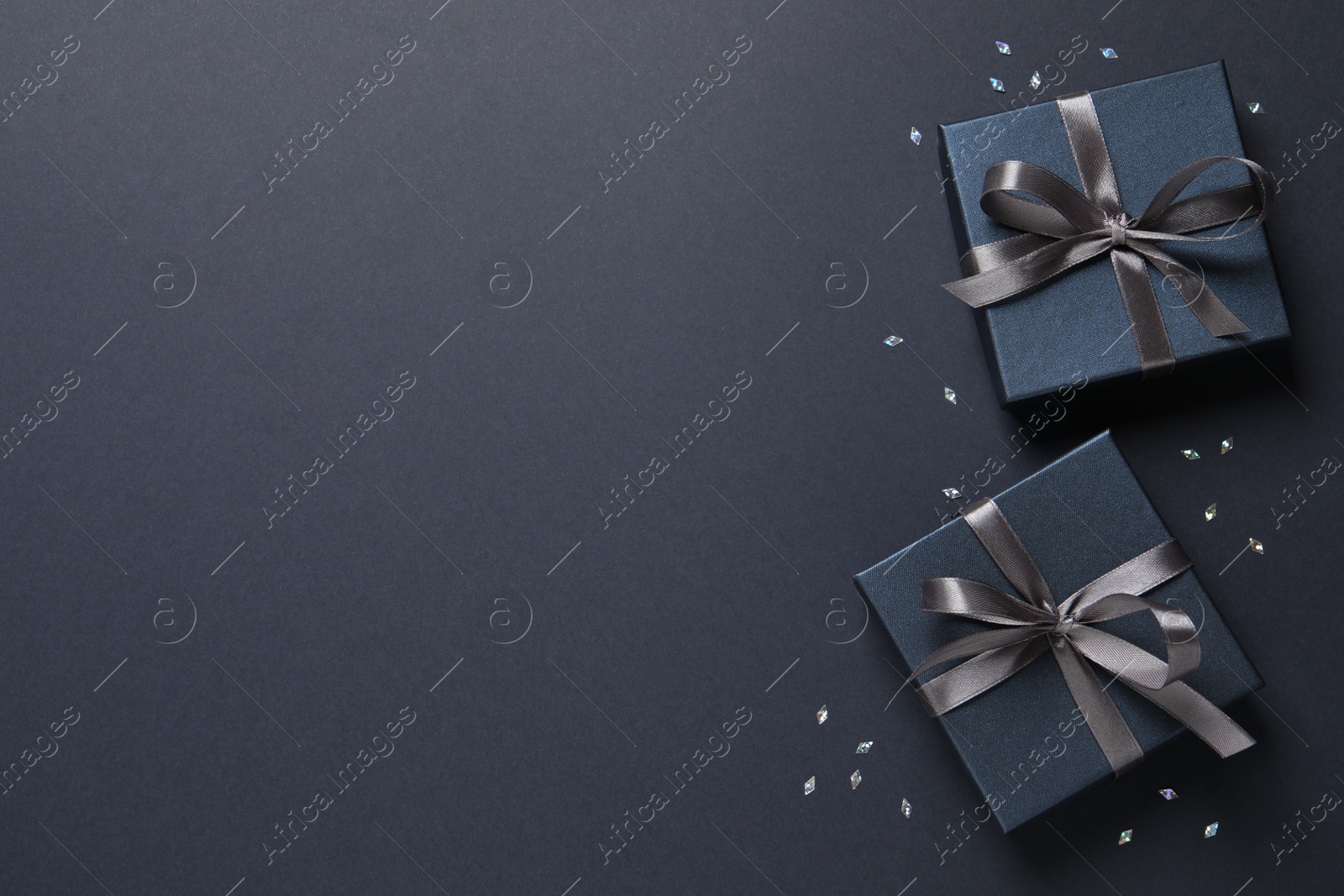 Photo of Beautiful gift boxes and confetti on black background, flat lay. Space for text