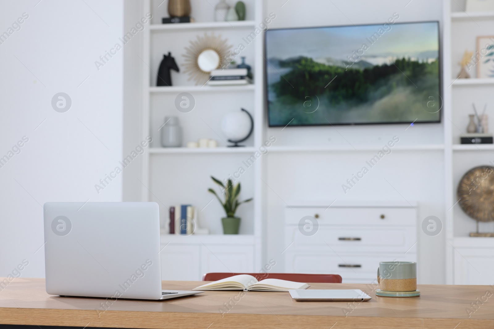Photo of Interior design. Cosy workplace with laptop and tablet near tv area