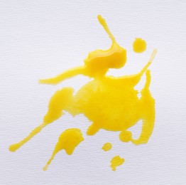 Photo of Blot of yellow ink on white background, top view