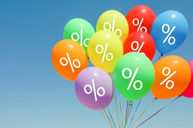 Image of Discount offer. Bunch of balloons with percent signs against blue sky