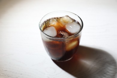 Photo of Refreshing iced coffee in glass on white wooden table