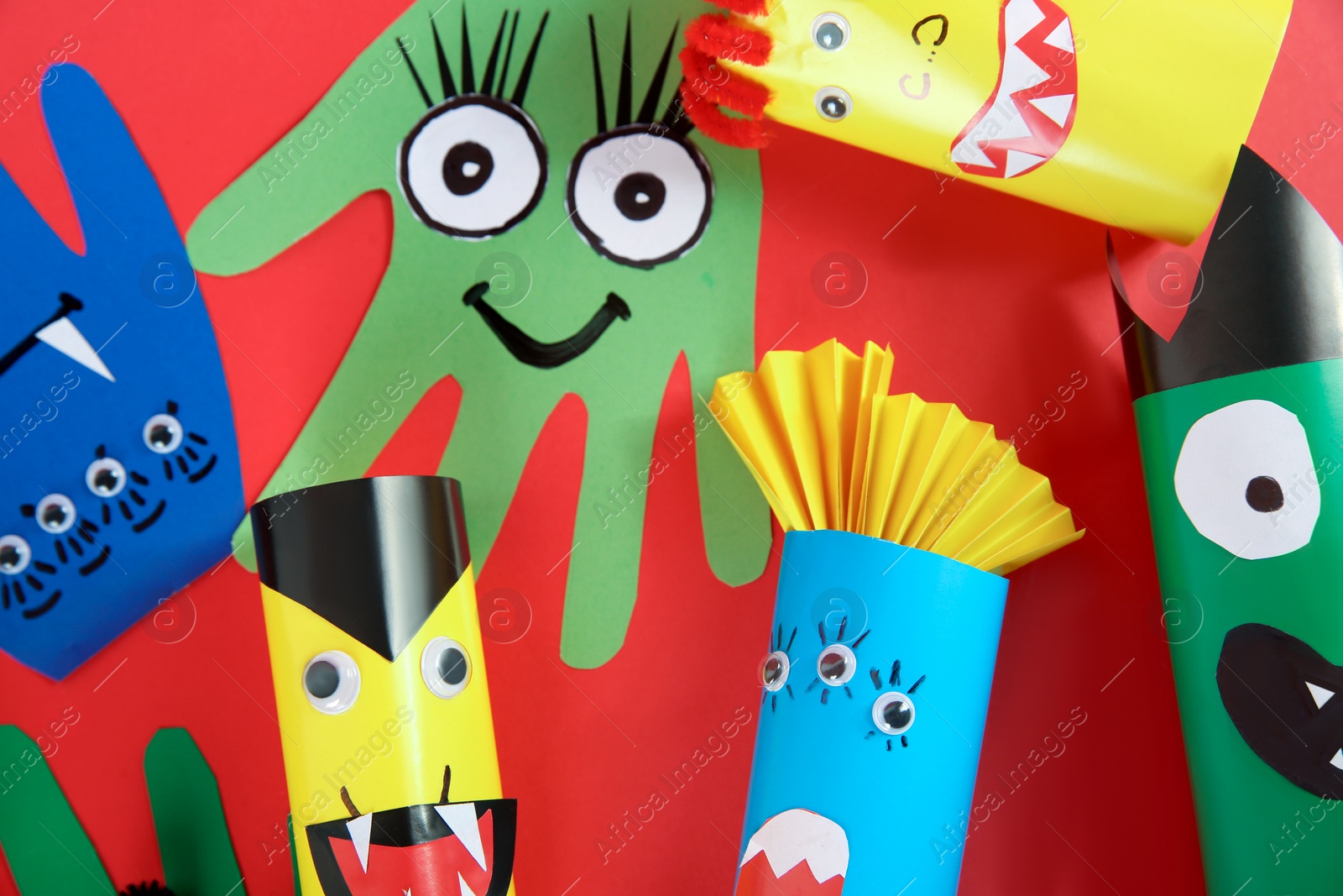 Photo of Funny monsters on red background, flat lay. Halloween decoration