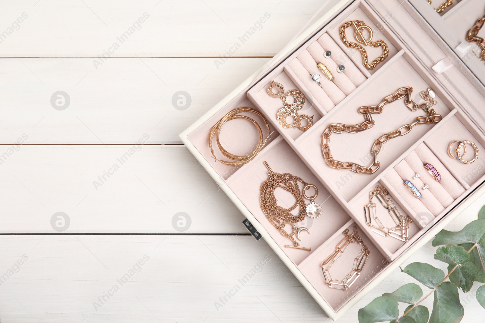 Photo of Jewelry box with stylish golden bijouterie on white wooden table, flat lay. Space for text