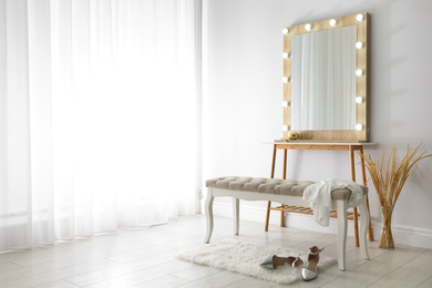 Photo of Stylish mirror with lamps near light wall in room