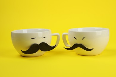 Photo of Men's faces made of cups, fake mustaches on yellow background