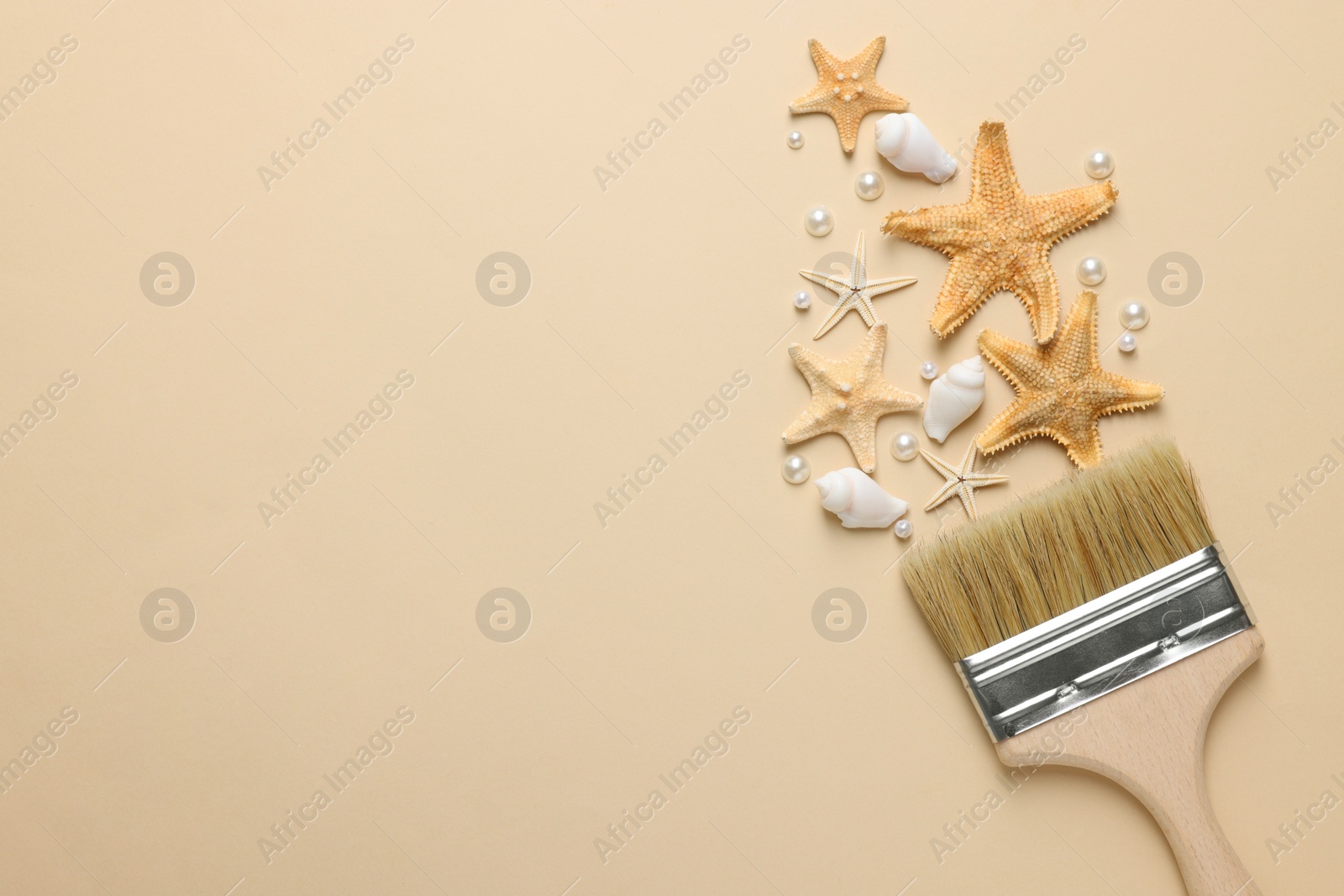 Photo of Brush painting with sea stars, pearls and shells on beige background, flat lay. Space for text. Creative concept