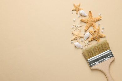 Photo of Brush painting with sea stars, pearls and shells on beige background, flat lay. Space for text. Creative concept