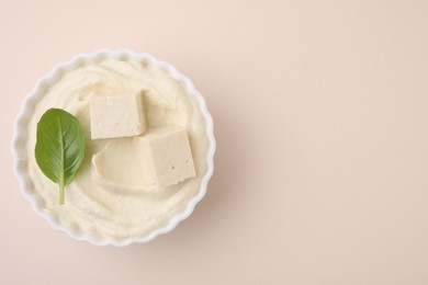 Delicious tofu sauce and basil leaf in bowl on beige background, top view. Space for text