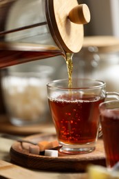 Photo of Pouring delicious tea into glass cup on table, closeup