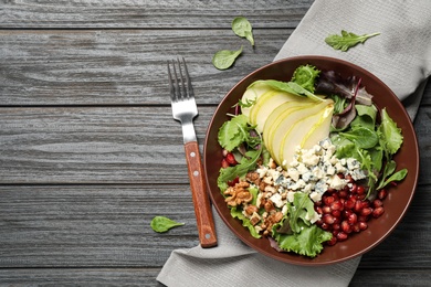 Photo of Tasty salad with pear slices served on black wooden table, flat lay. Space for text