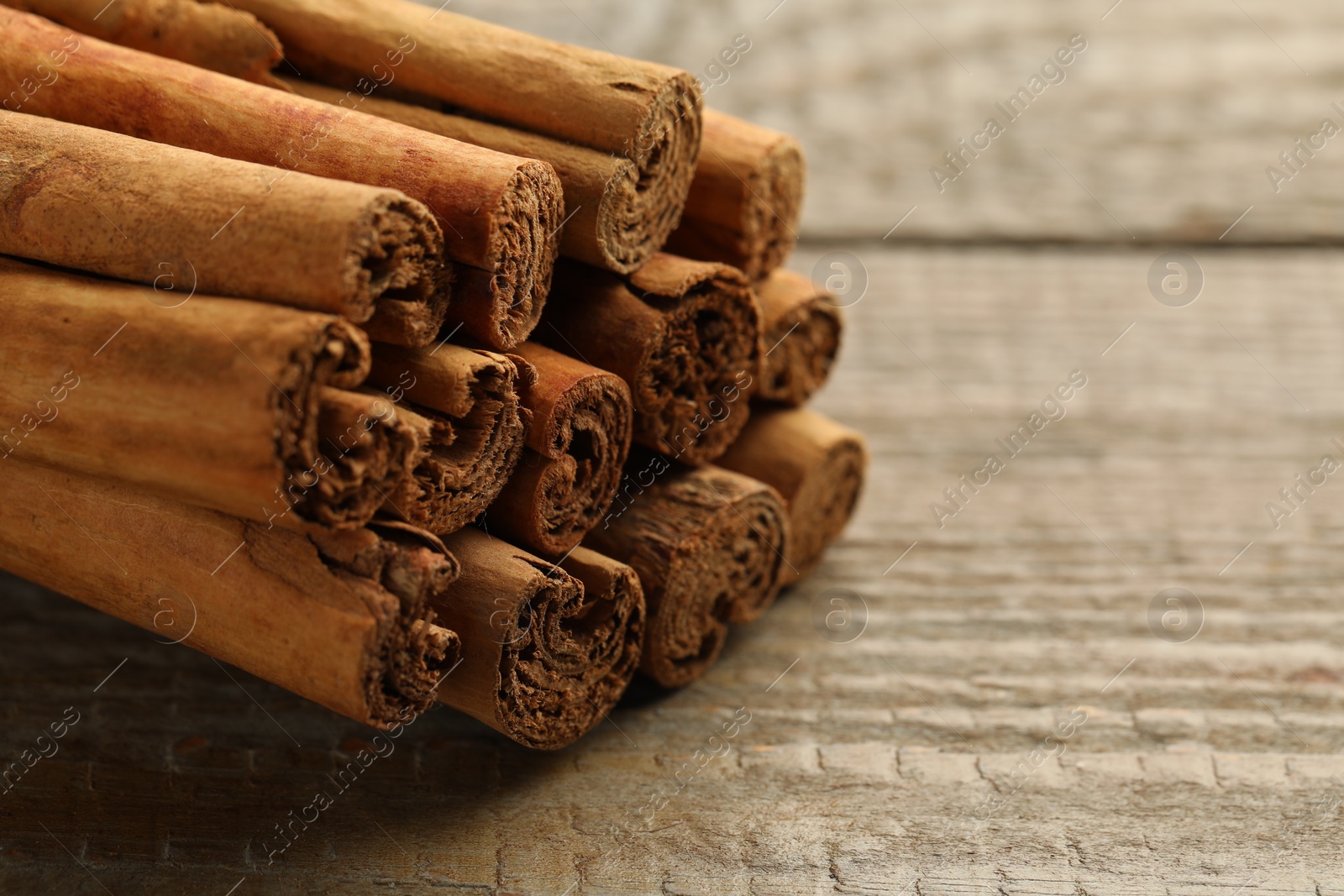 Photo of Cinnamon sticks on wooden table, closeup. Space for text