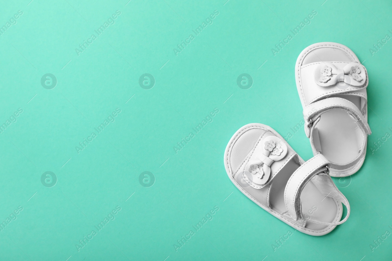 Photo of Pair of white baby sandals on color background, top view