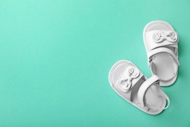 Pair of white baby sandals on color background, top view