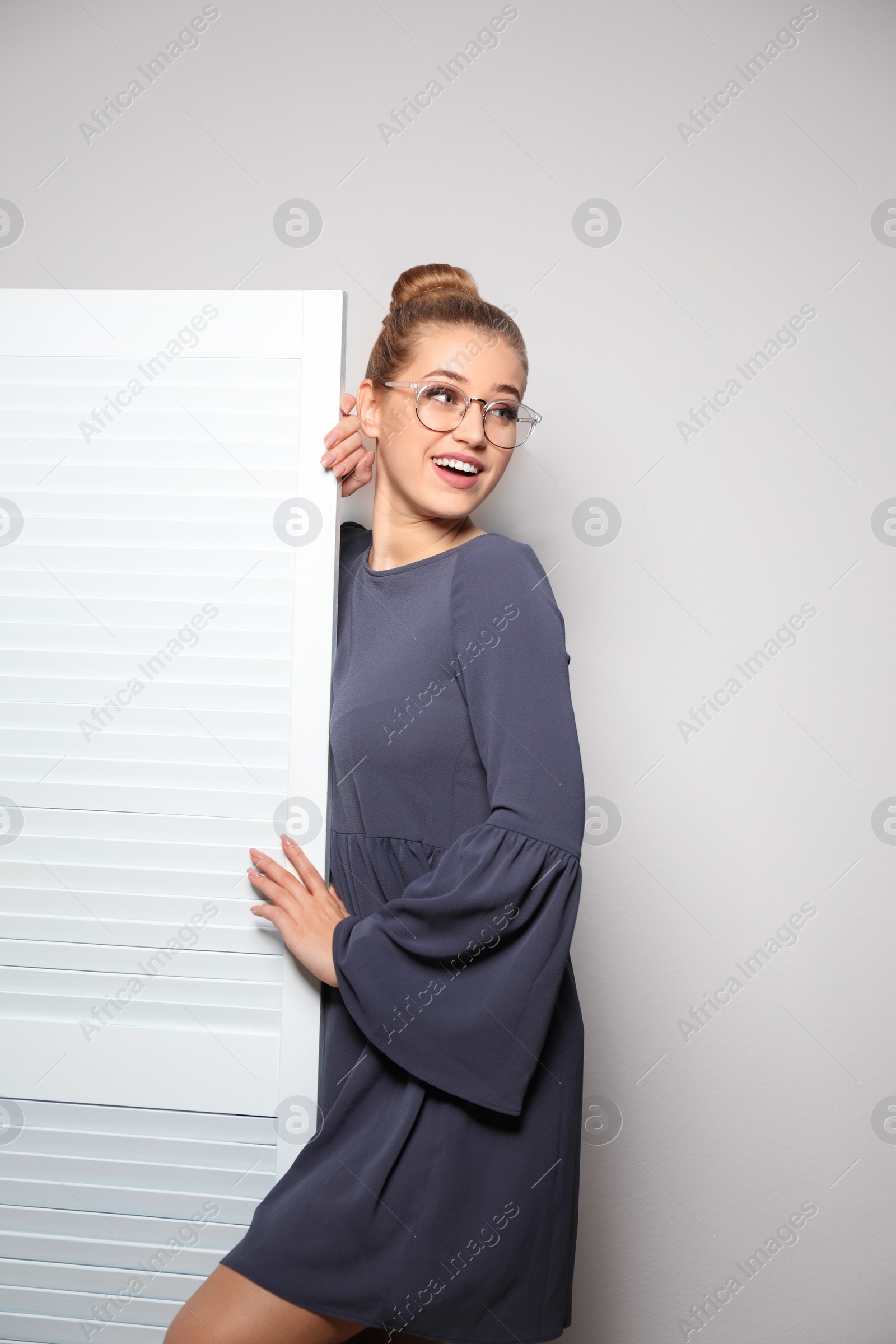 Photo of Young woman near folding screen against light background. Dressing room