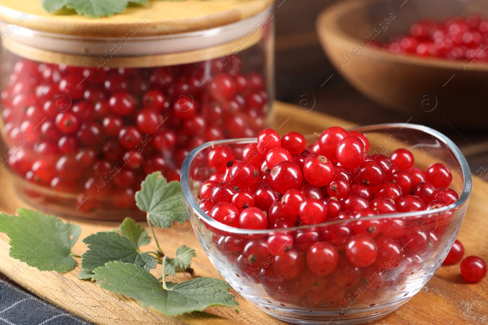 Photo of Ripe red currants and leaves on table, closeup
