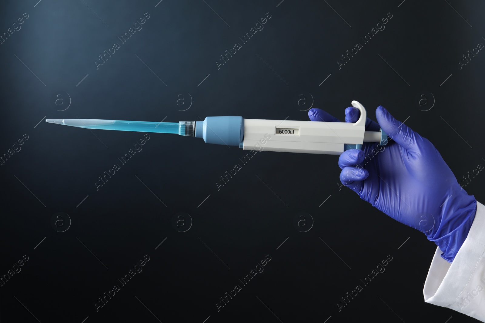 Photo of Laboratory analysis. Scientist holding micropipette with liquid on dark background, closeup