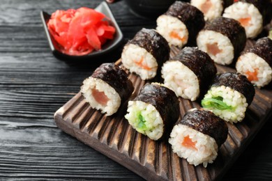 Tasty sushi rolls served on black wooden table, closeup
