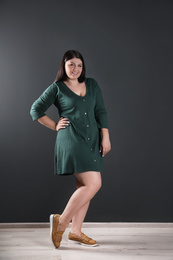 Photo of Beautiful overweight woman posing near black wall. Plus size model