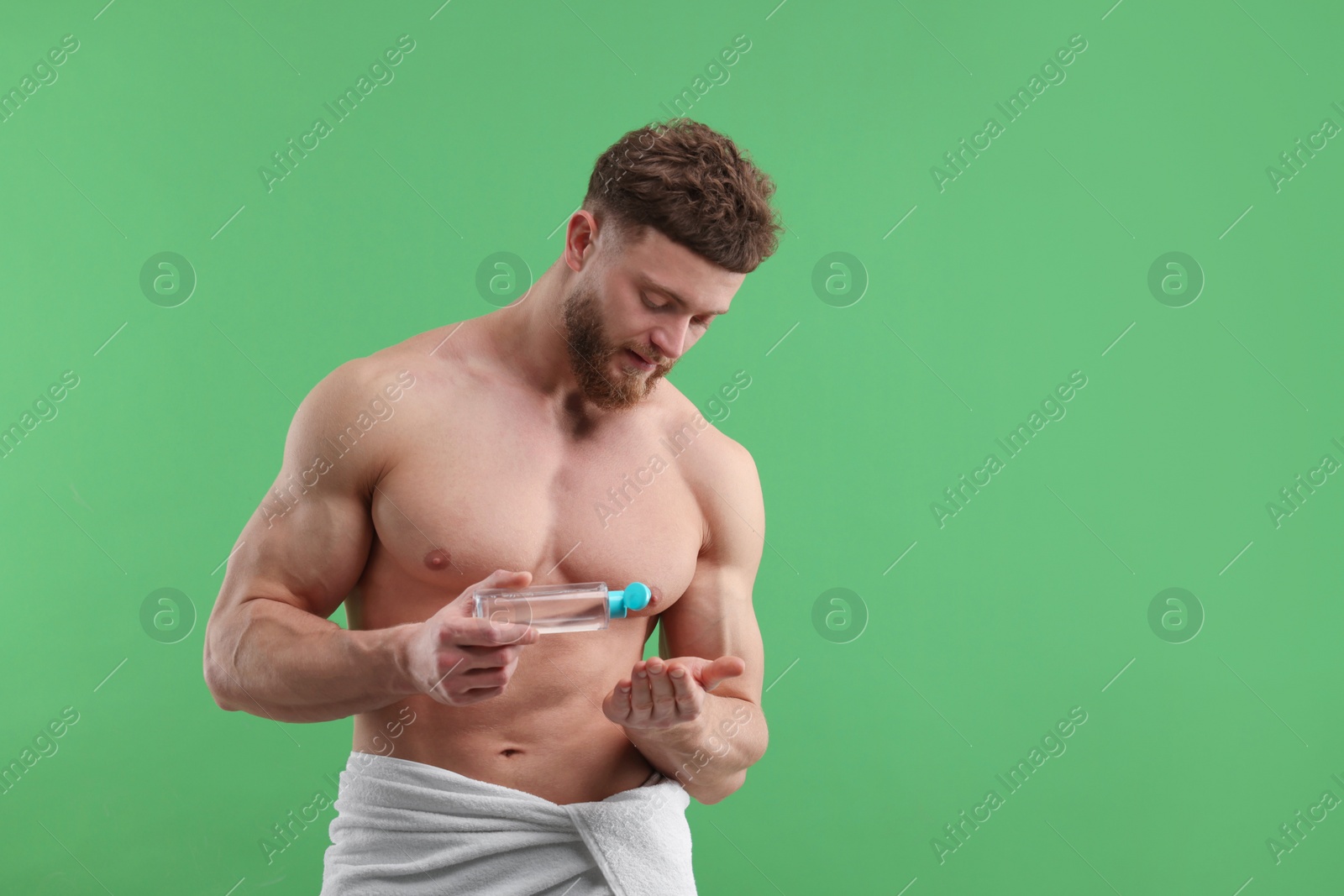 Photo of Handsome man with body lotion on green background, space for text
