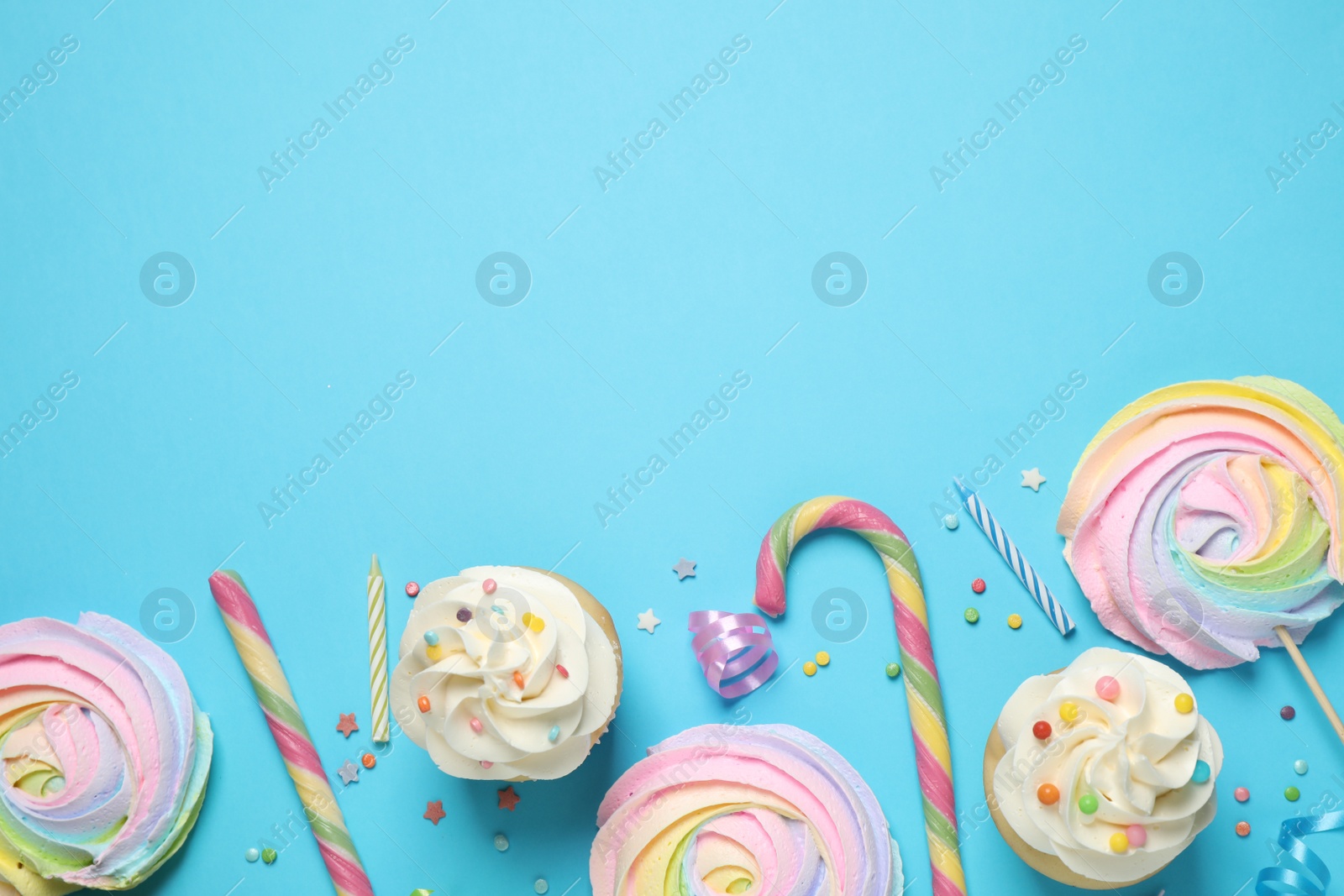 Photo of Flat lay composition with cupcakes on light blue background, space for text. Birthday party