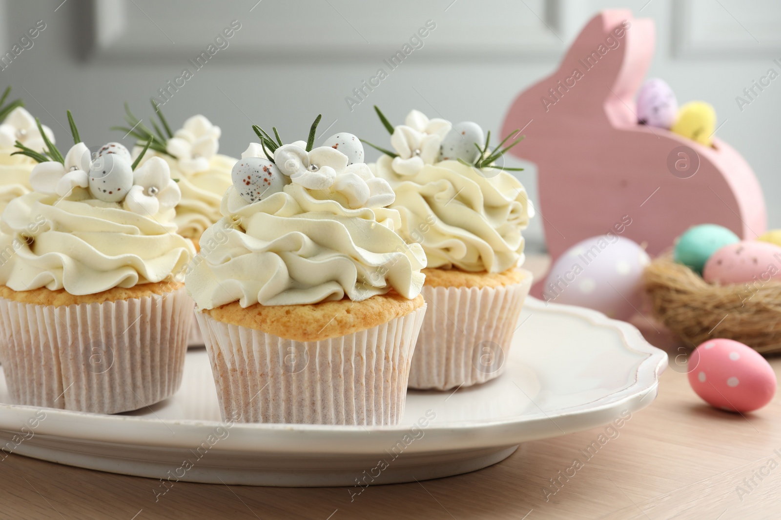 Photo of Tasty Easter cupcakes with vanilla cream on wooden table, closeup