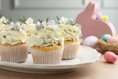 Tasty Easter cupcakes with vanilla cream on wooden table, closeup