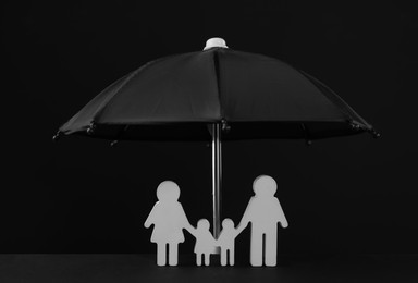 Small umbrella and family figure on black background