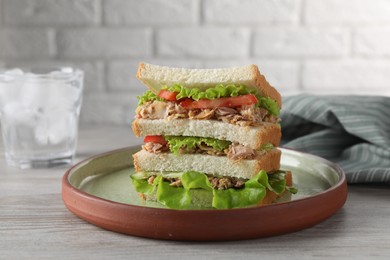 Delicious sandwich with tuna, tomatoes and lettuce on white wooden table