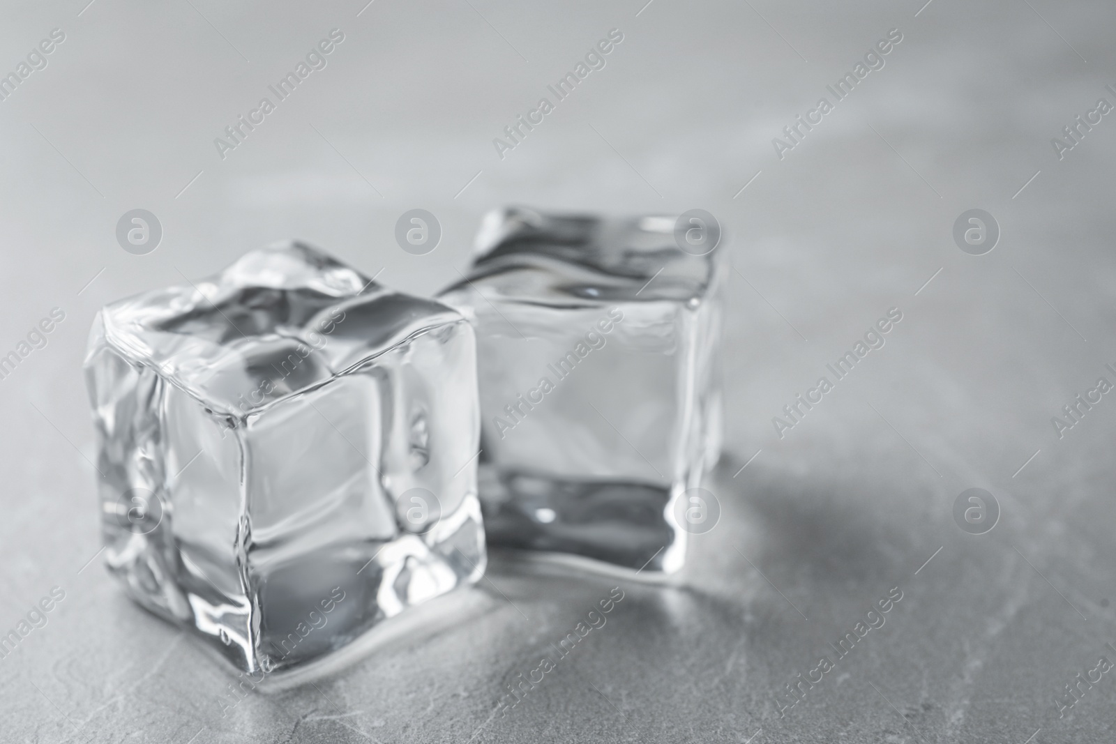 Photo of Crystal clear ice cubes on grey table, closeup