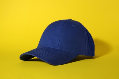 Photo of Stylish blue baseball cap on yellow background