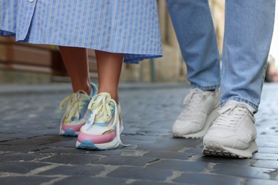 Photo of Woman and man wearing stylish sneakers on city street, closeup