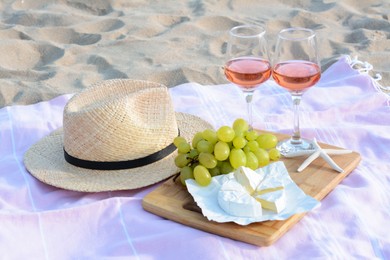 Glasses with rose wine and snacks for beach picnic on sand outdoors