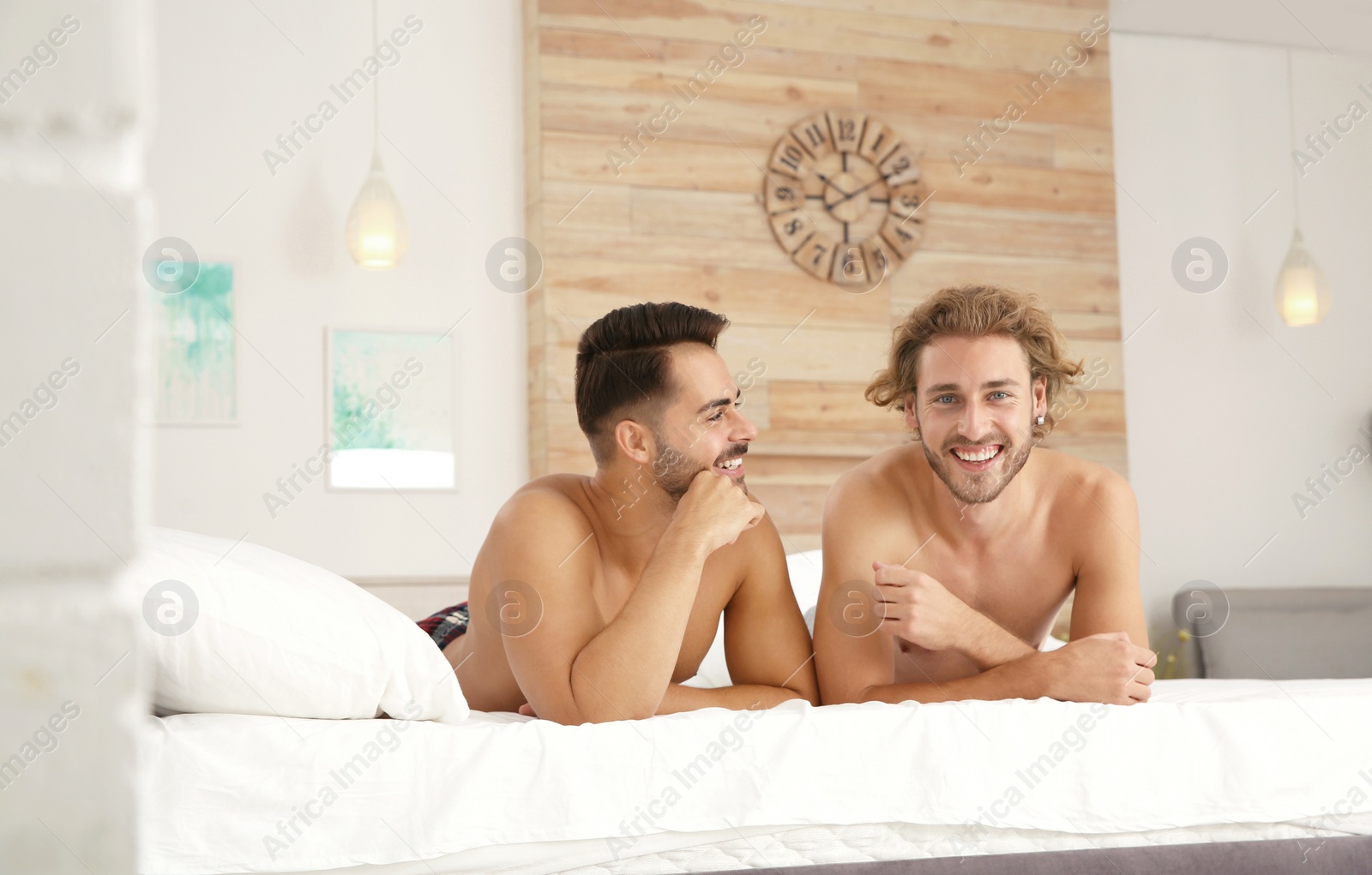 Photo of Happy gay couple lying on bed at home