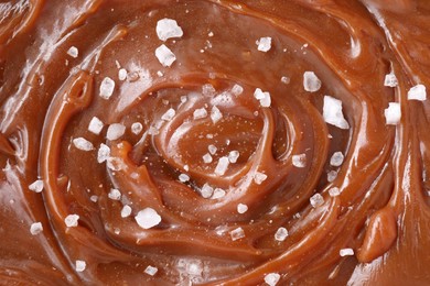 Photo of Tasty caramel sauce and salt as background, top view