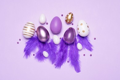 Flat lay composition with festively decorated Easter eggs on lilac background