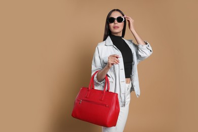 Young woman with stylish bag on beige background, space for text