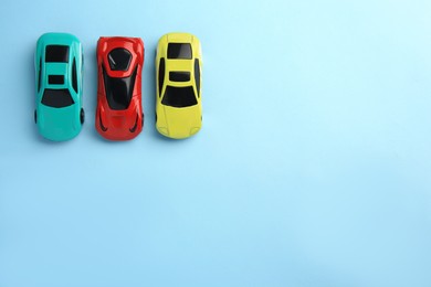 Photo of Different bright cars on light blue background, flat lay with space for text. Children`s toys