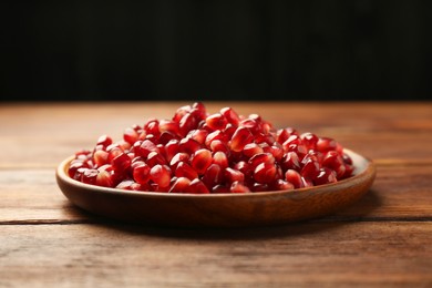 Photo of Tasty ripe pomegranate grains on wooden table