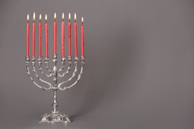 Photo of Silver menorah with burning candles on grey background, space for text. Hanukkah celebration