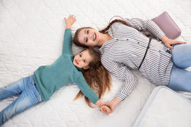 Photo of Mother and daughter testing mattress in store, top view