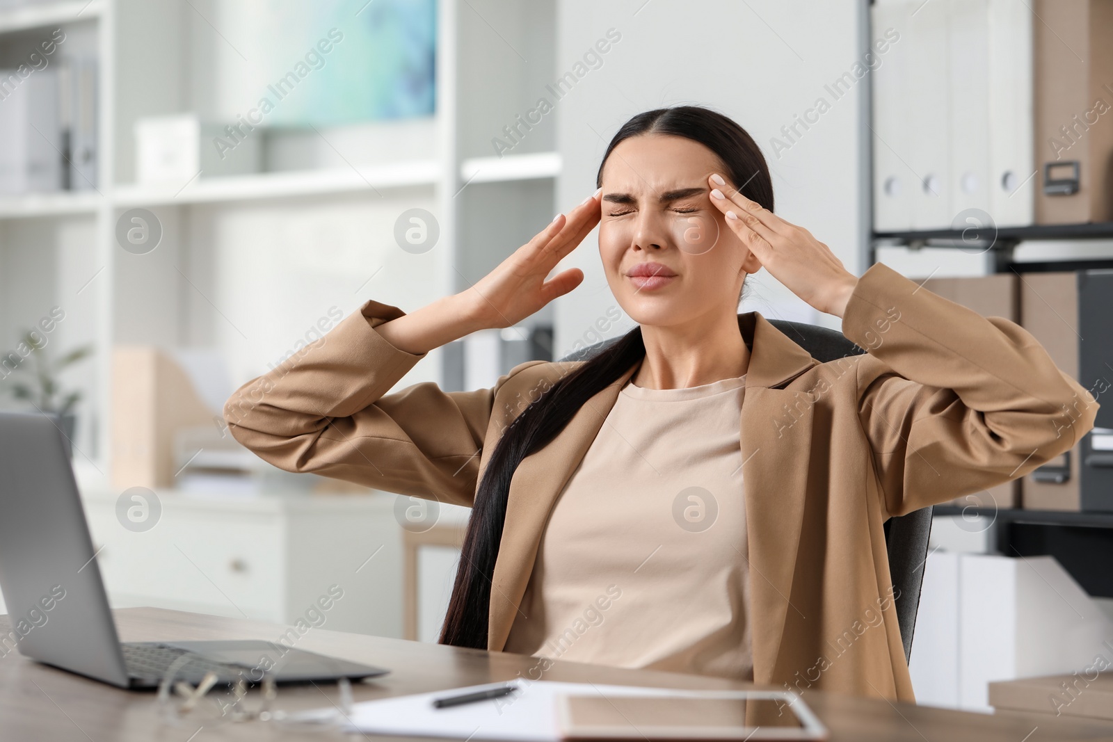 Photo of Woman suffering from headache at workplace in office