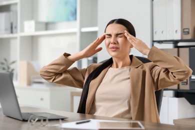 Woman suffering from headache at workplace in office