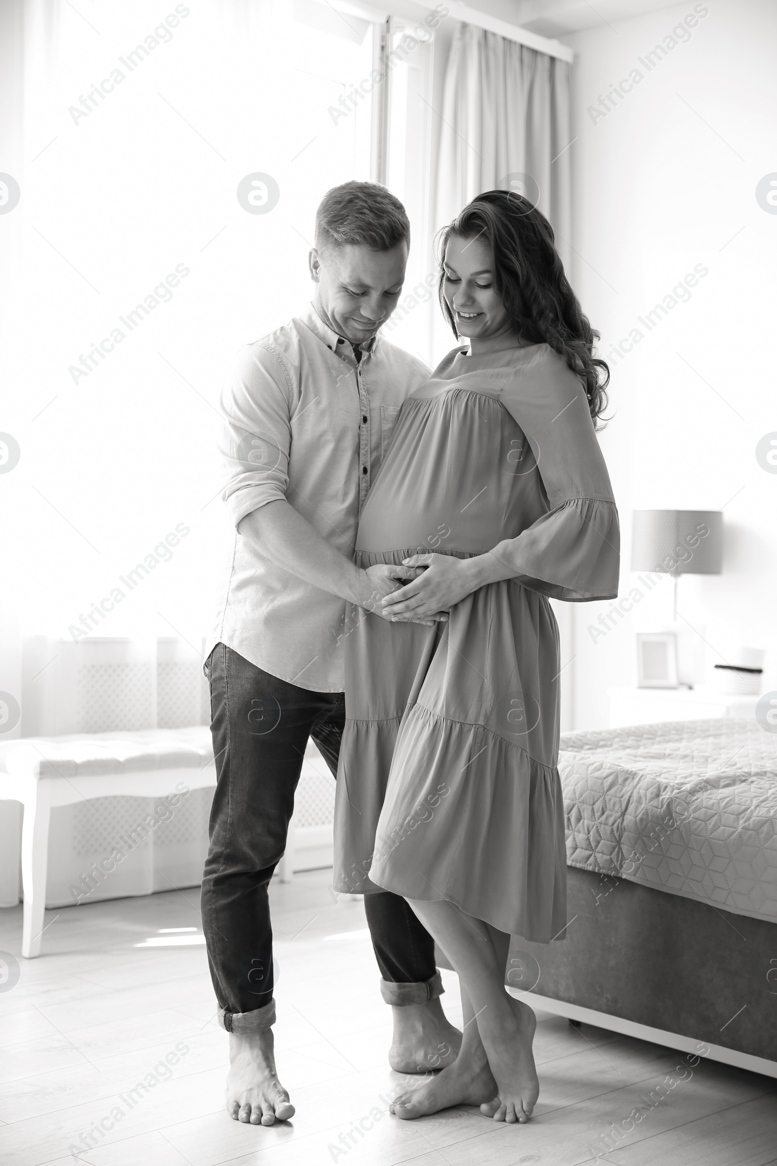Photo of Pregnant woman with her husband in bedroom, black and white effect