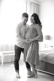 Pregnant woman with her husband in bedroom, black and white effect