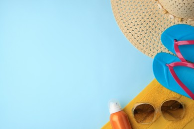 Photo of Flat lay composition with sunscreen and different beach accessories on light blue background. Space for text