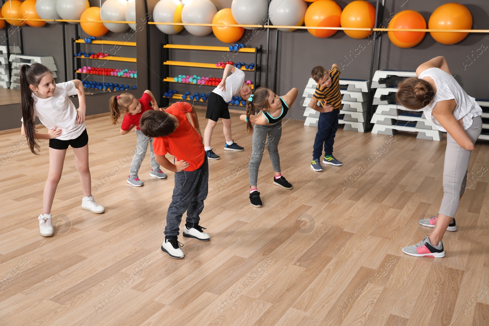 Photo of Cute little children and trainer doing physical exercise in school gym. Healthy lifestyle