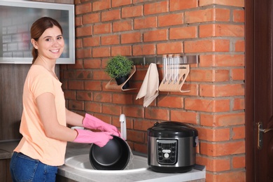 Woman washing modern multi cooker in kitchen sink